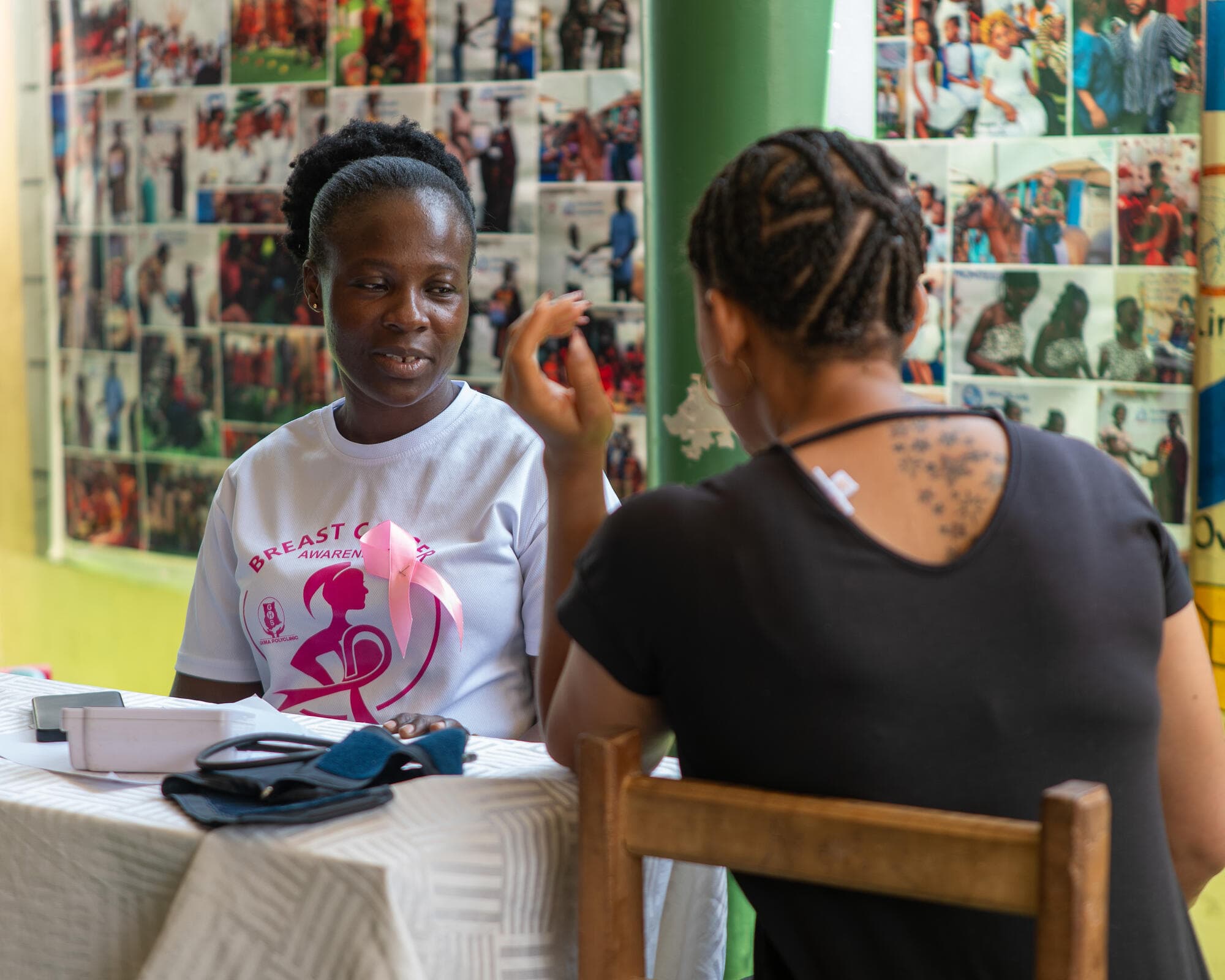 A health volunteer wearing a Breast Cancer Awareness t-shirt speaking with a community member