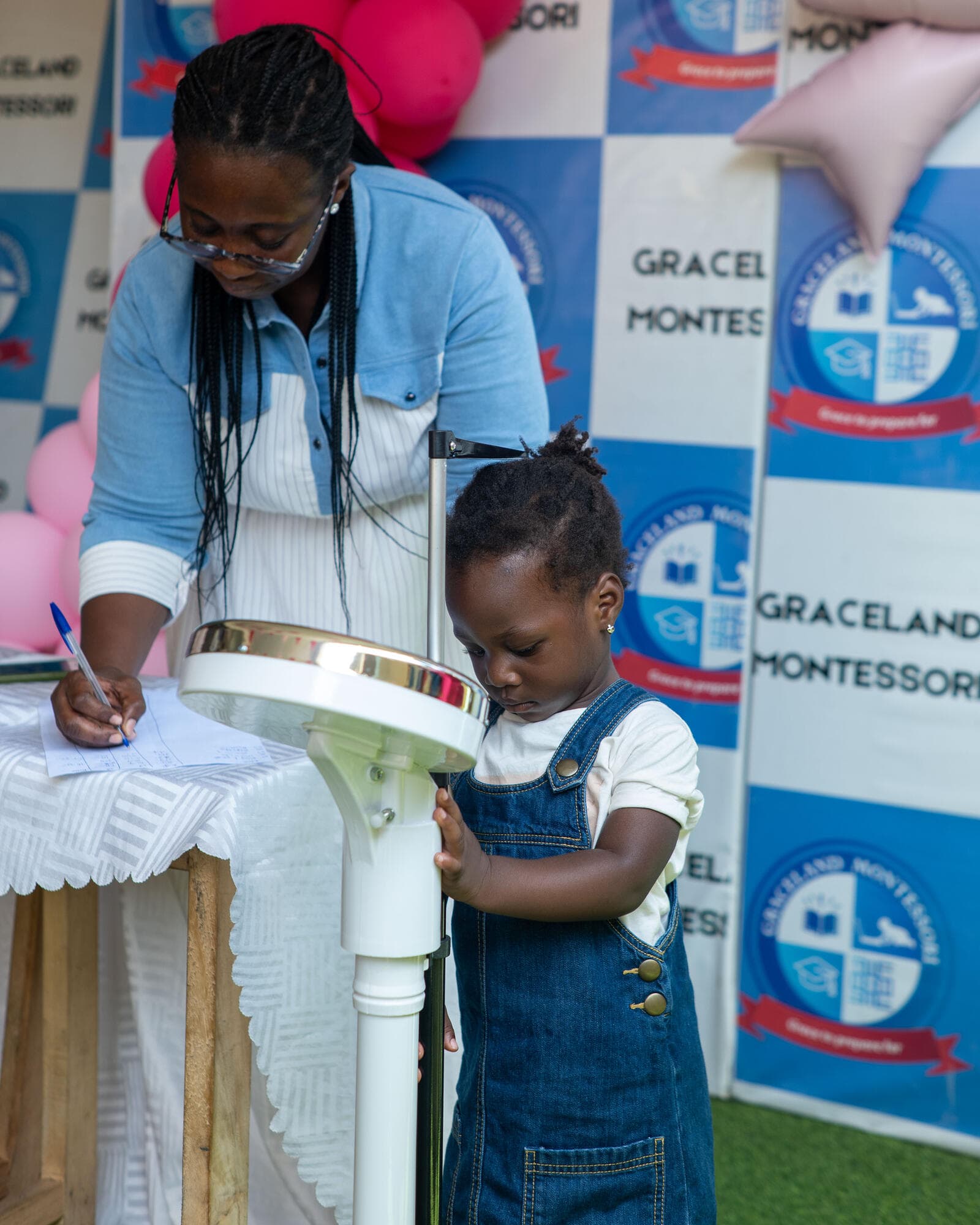 A toddler being measured on a height scale by a staff member