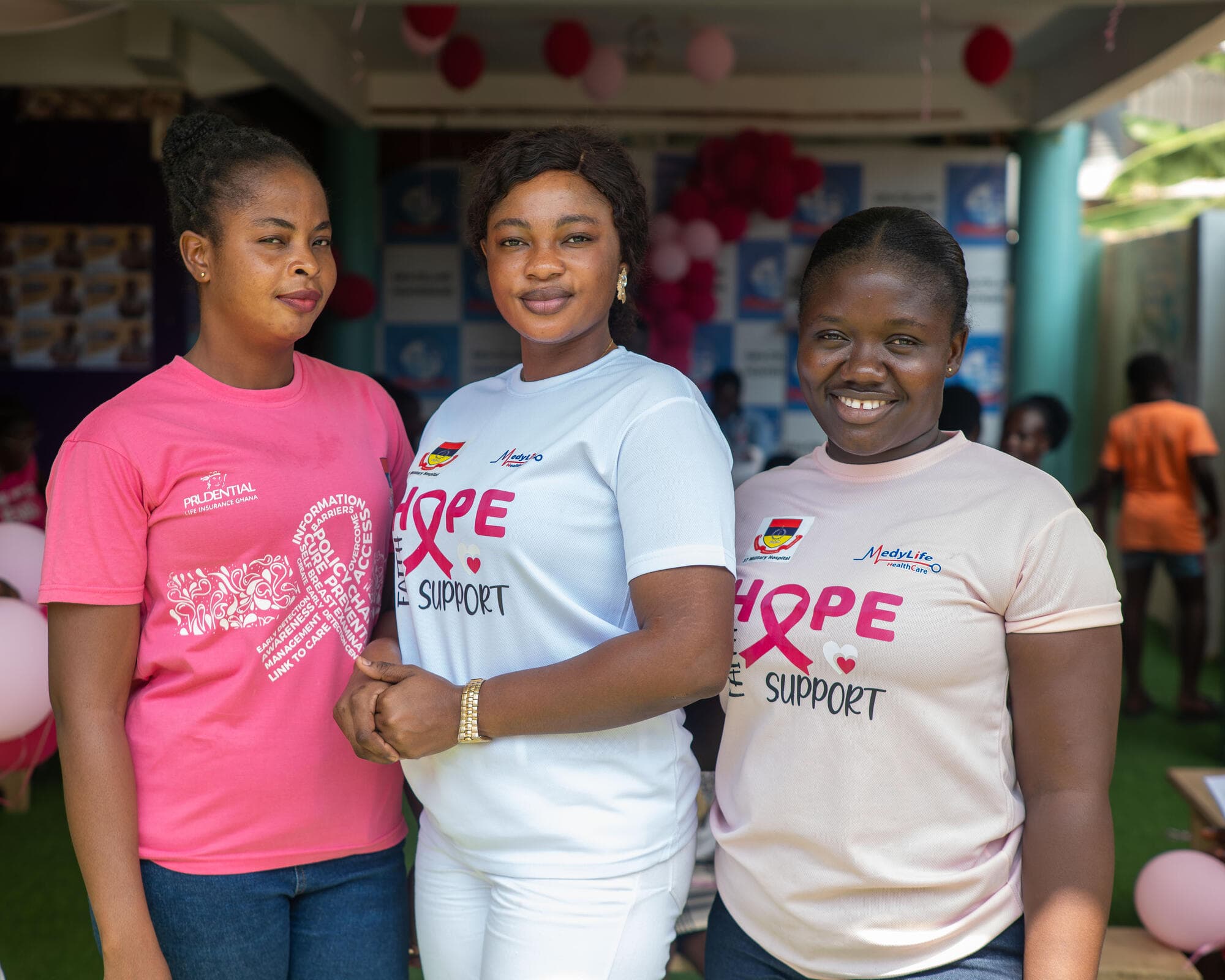 A group of health volunteers wearing pink 'Hope, Faith, Support' t-shirts