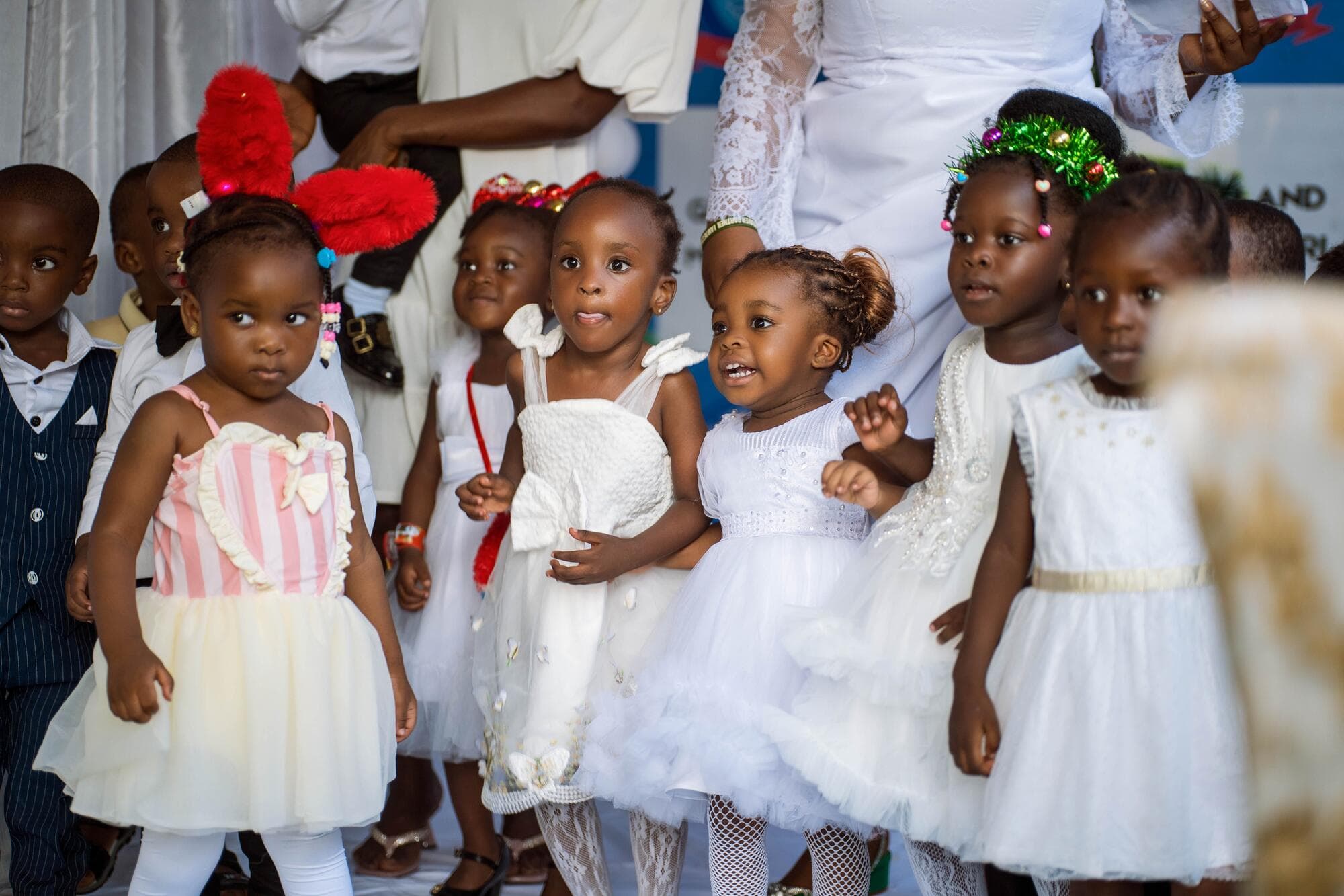 A line of toddlers in white dresses walking together at the Carols Day celebration