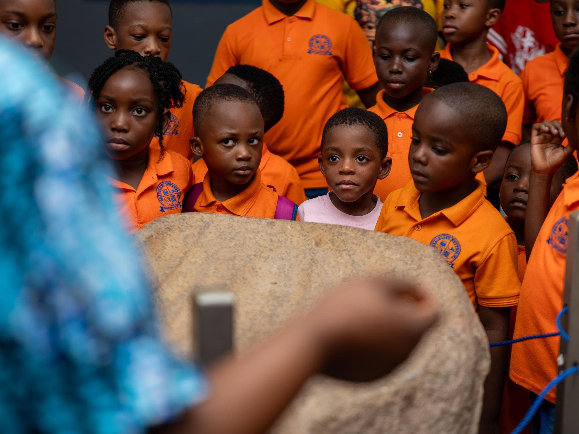 Children gathered around a traditional grinding stone exhibit at the Ghana National Museum