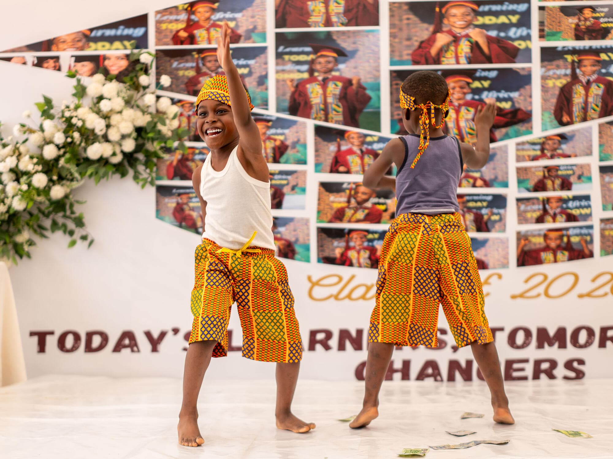 Two pupils performing a dance in kente cloth on stage