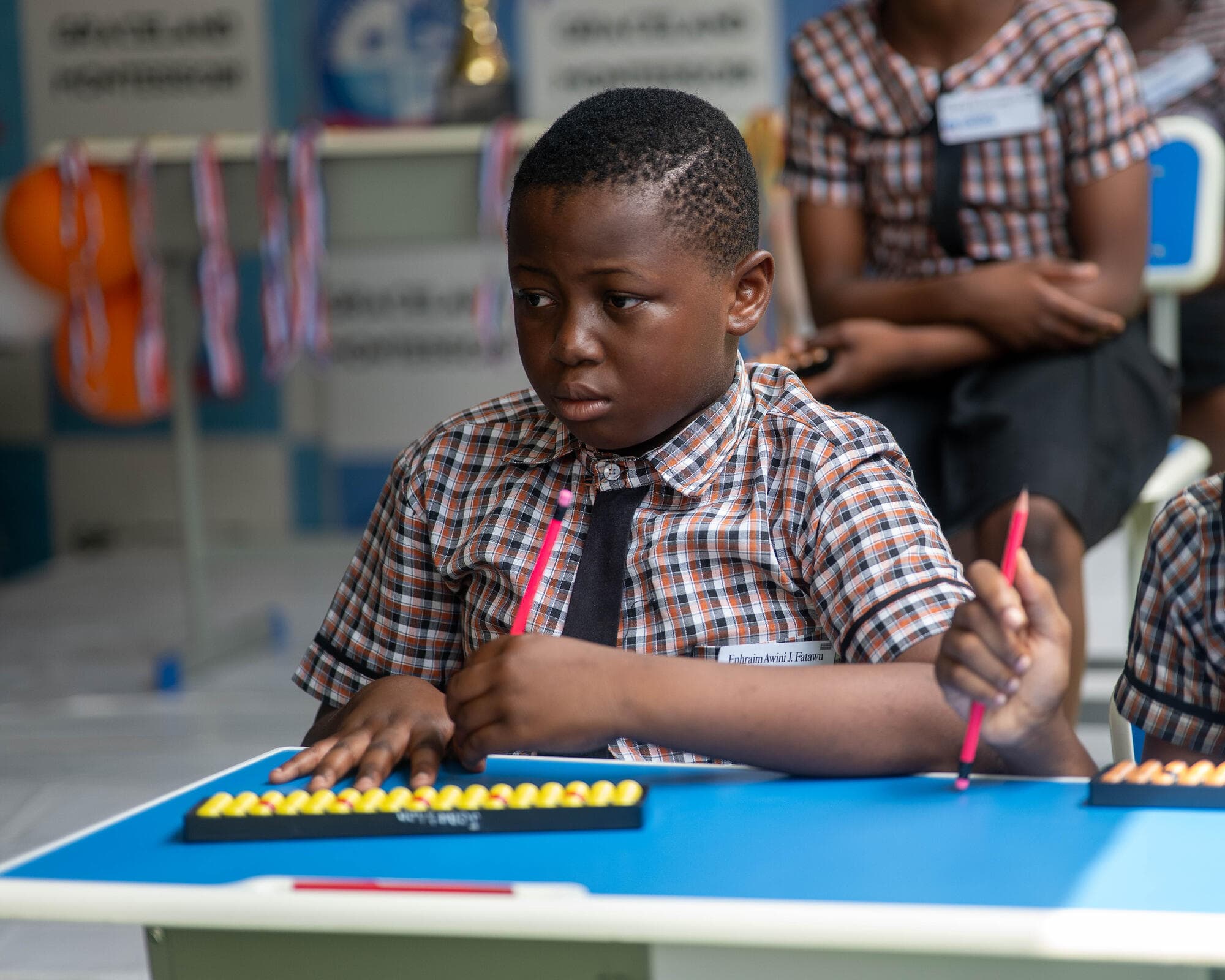A Graceland pupil concentrating closely while using an abacus tool during the competition