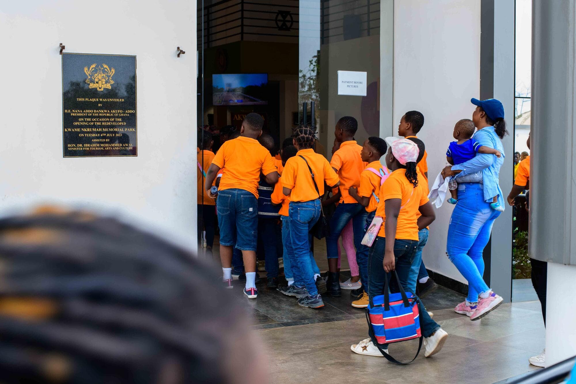 Pupils filing in past the plaque marking the Kwame Nkrumah Memorial Park entrance