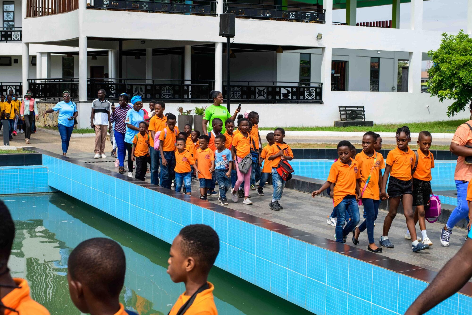 Pupils walking in a line beside a long reflecting pool on the memorial grounds