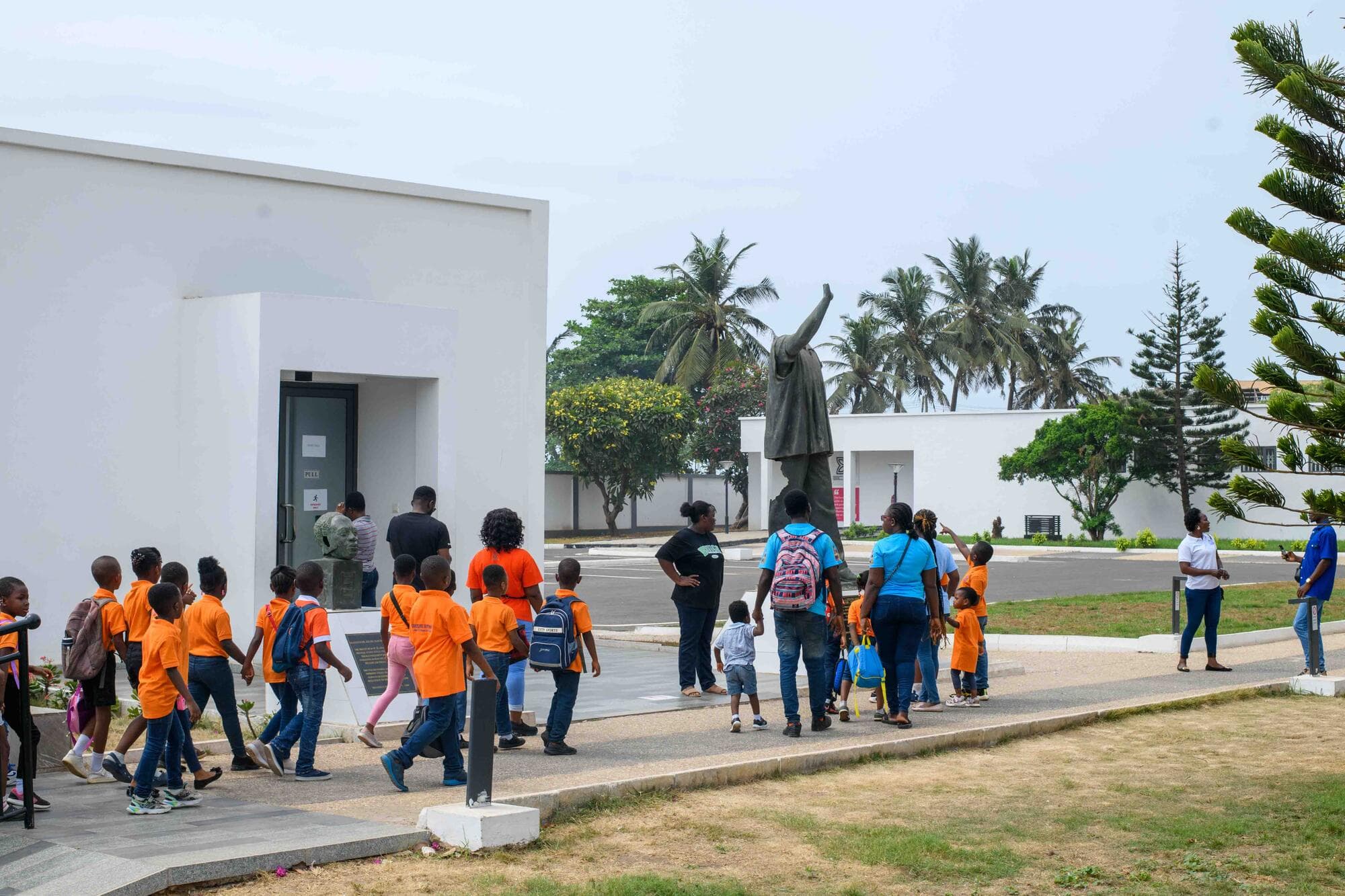 Pupils and staff walking across the grounds toward the bronze statue of Kwame Nkrumah