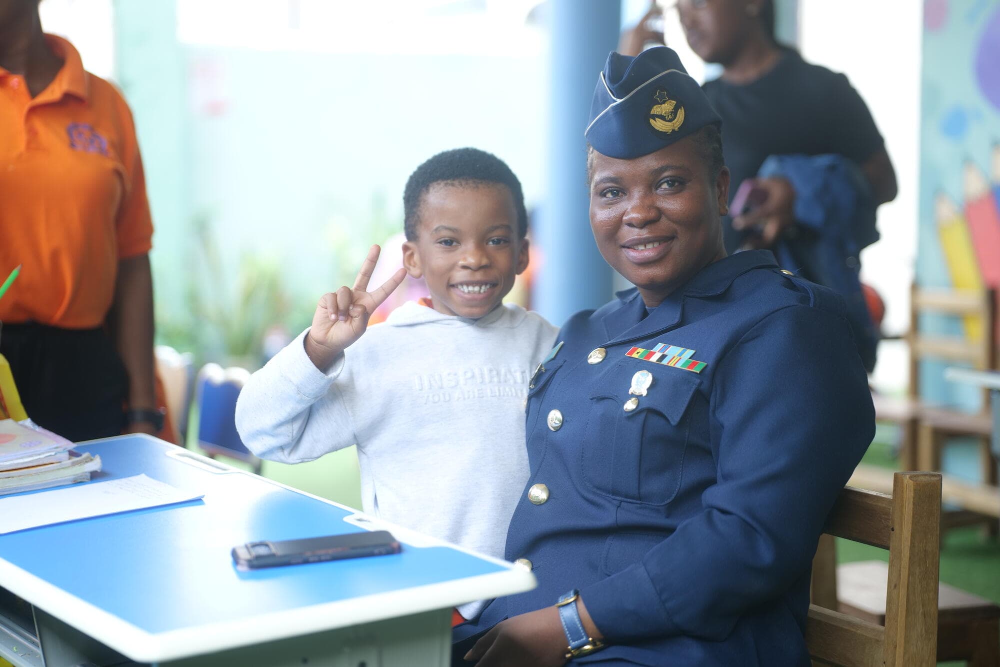 A smiling pupil making a peace sign next to his parent