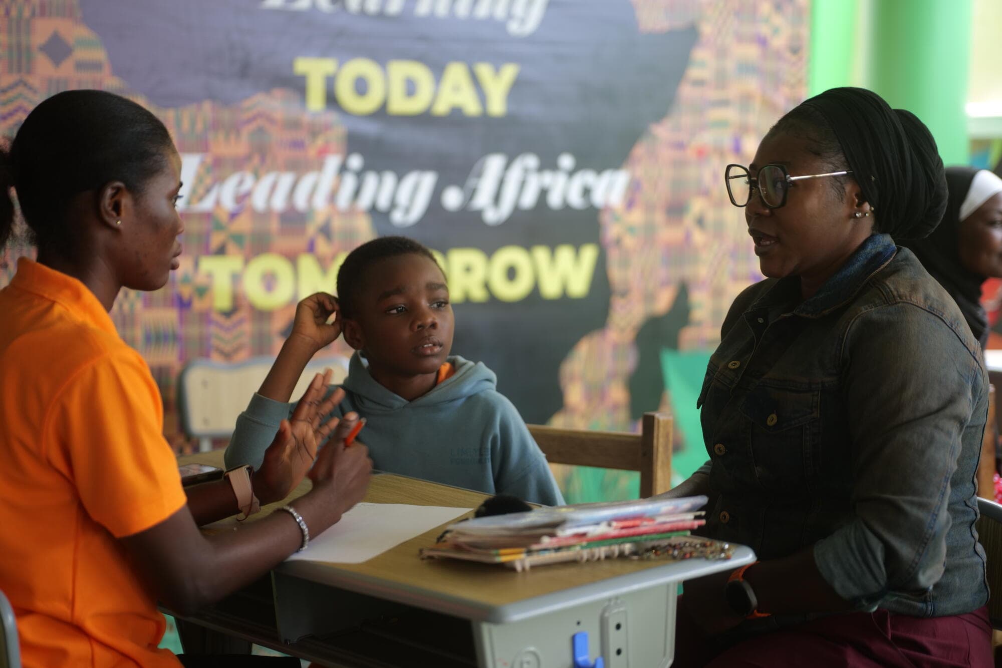 A teacher speaking with a parent and her son during a one-on-one PTA consultation