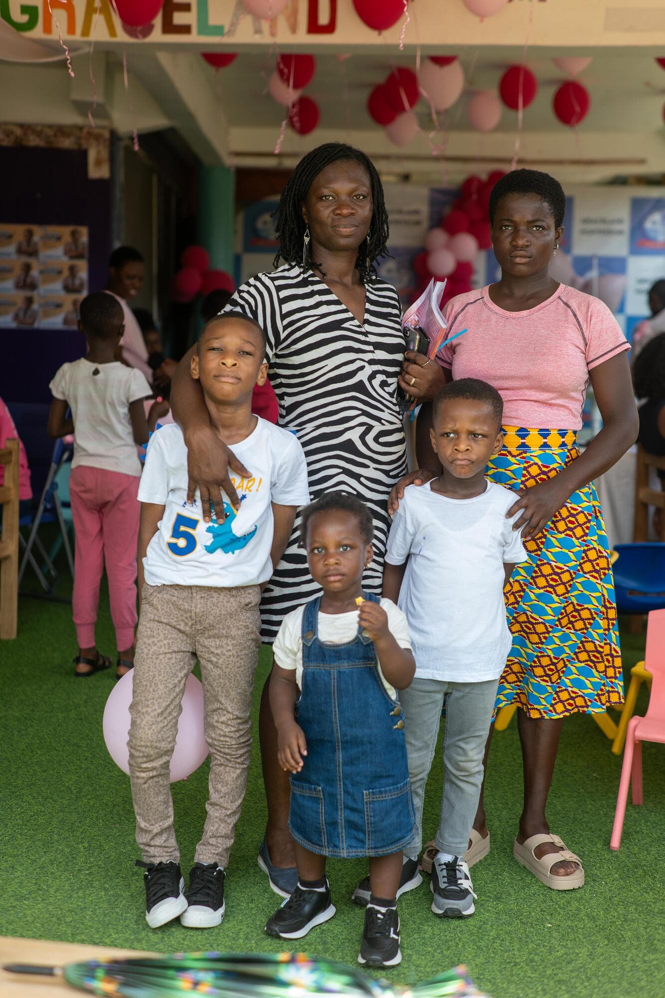 A mother with four children posing together at the event, decorated with pink and white balloons