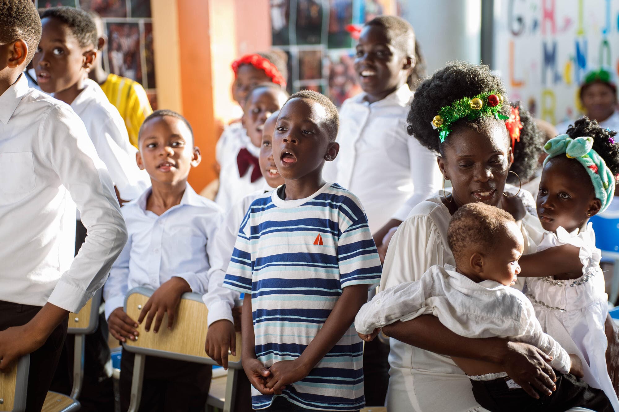 Pupils singing together as a parent holds a baby nearby