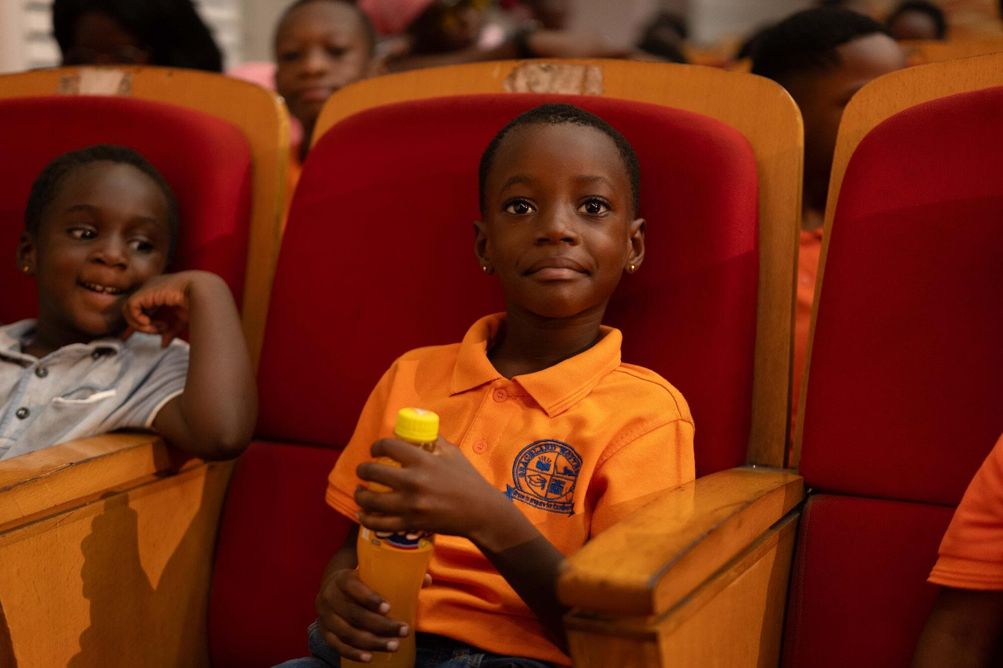 A Graceland pupil sitting in a theatre seat holding a drink, watching the day's performances