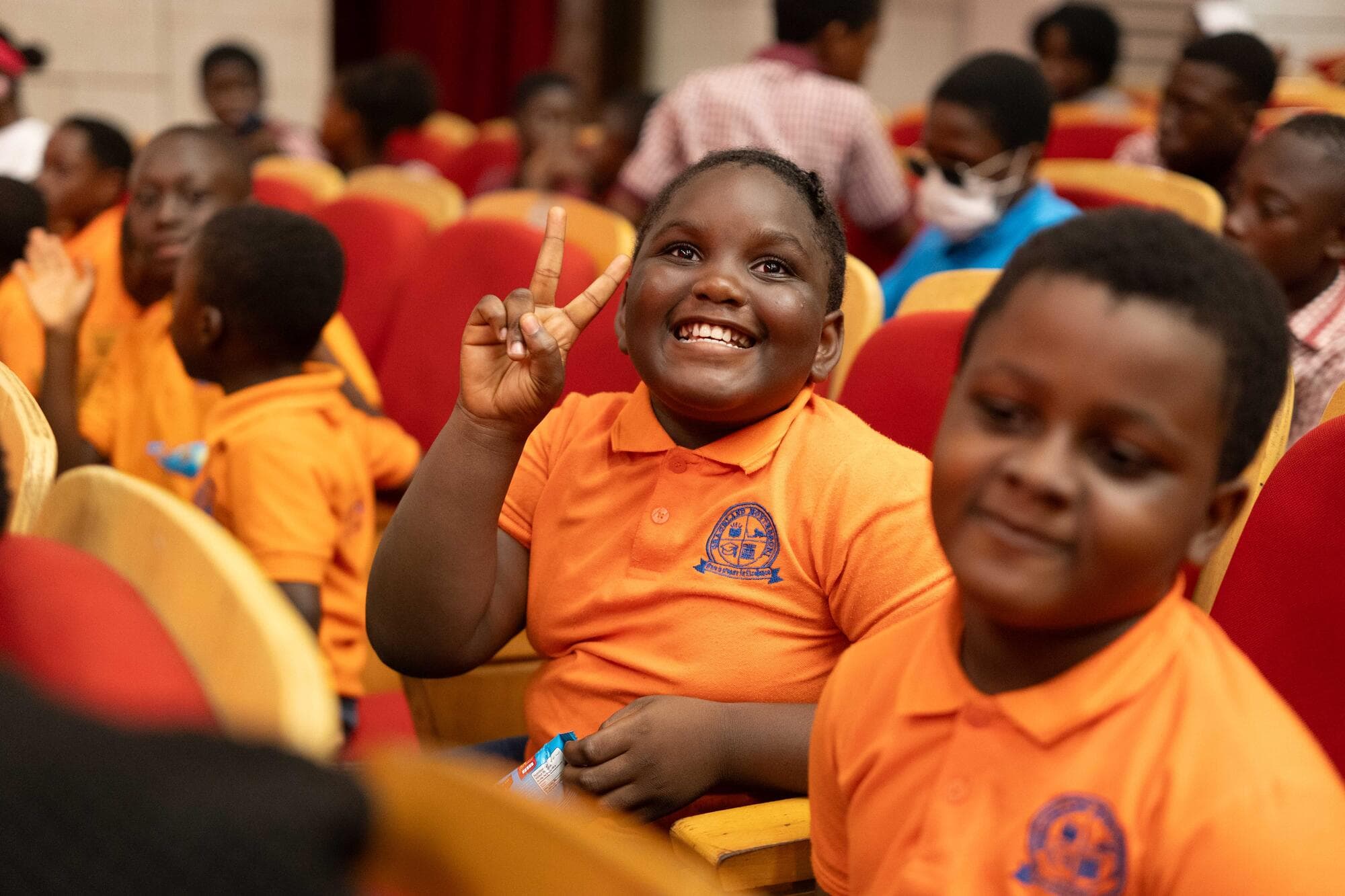 A smiling Graceland pupil making a peace sign from her theatre seat