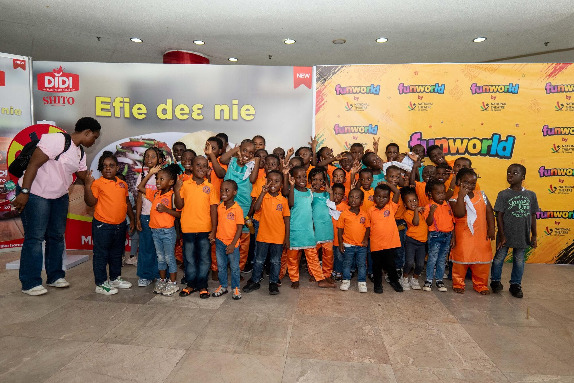 A large group of Graceland pupils posing together in the National Theatre lobby in front of the FUNWORLD banner