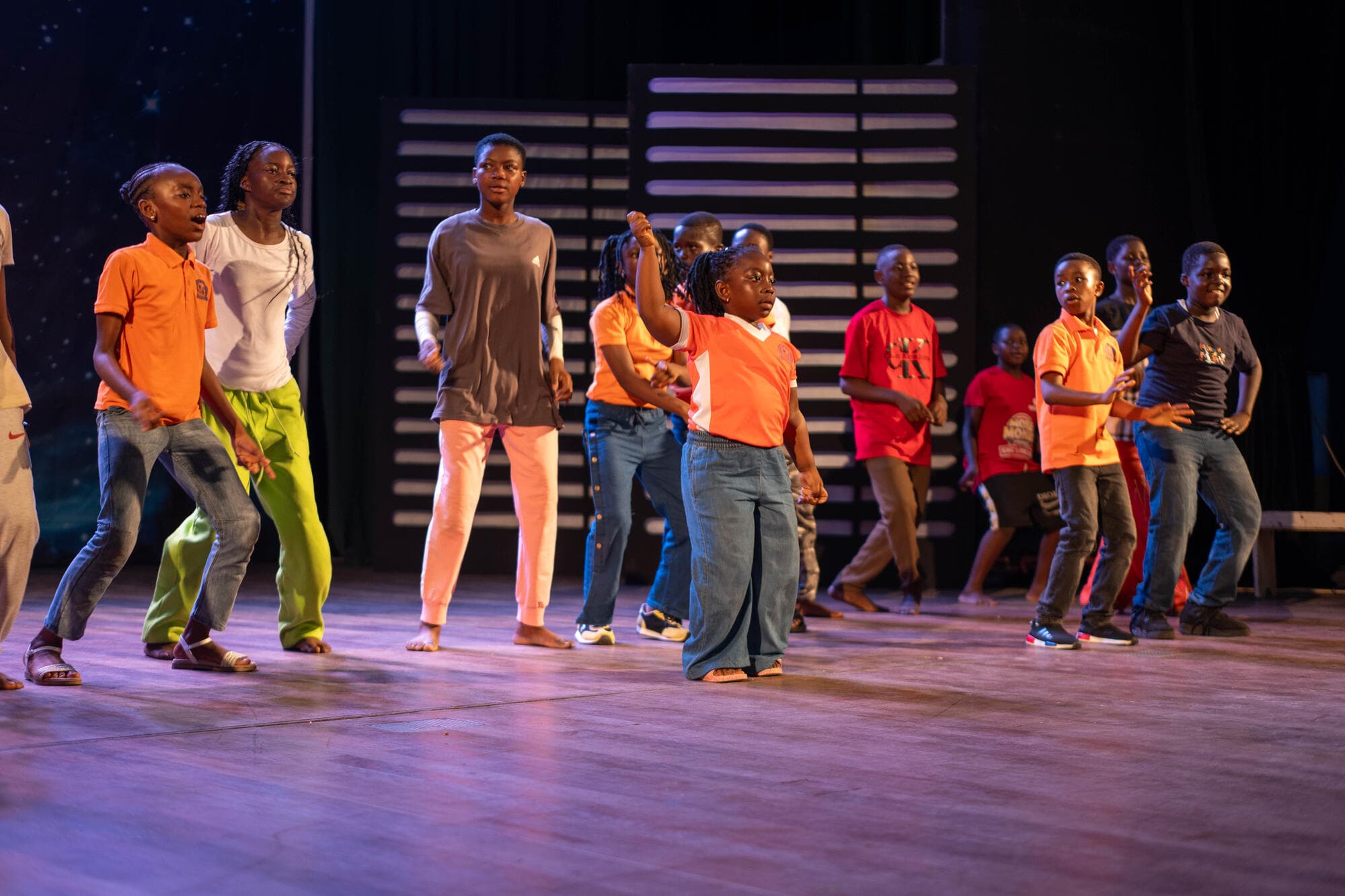 Graceland pupils dancing with arms raised during rehearsal on stage