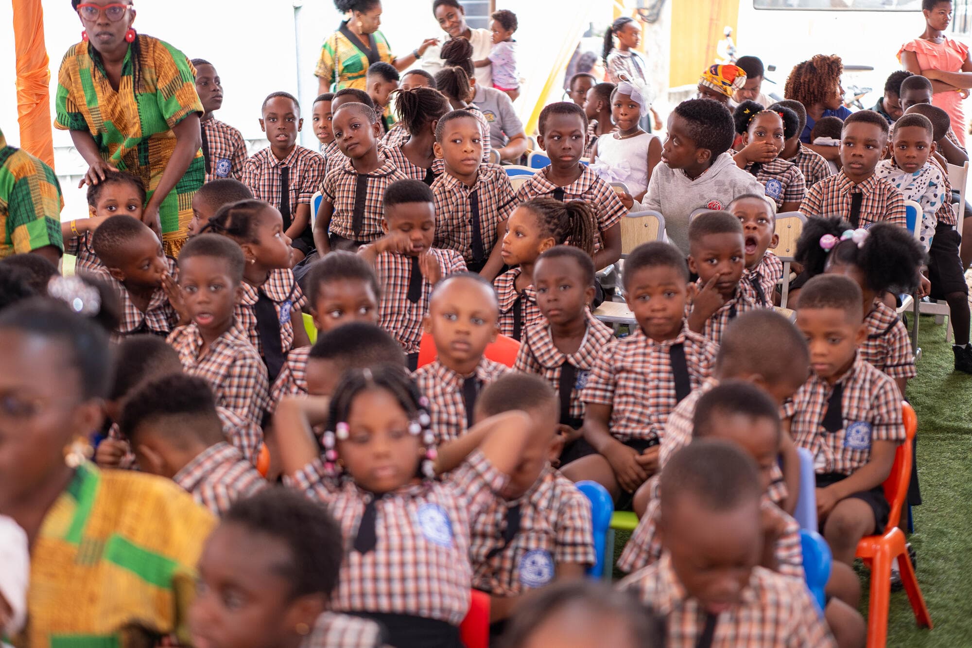 Rows of pupils in checkered uniforms seated in the audience