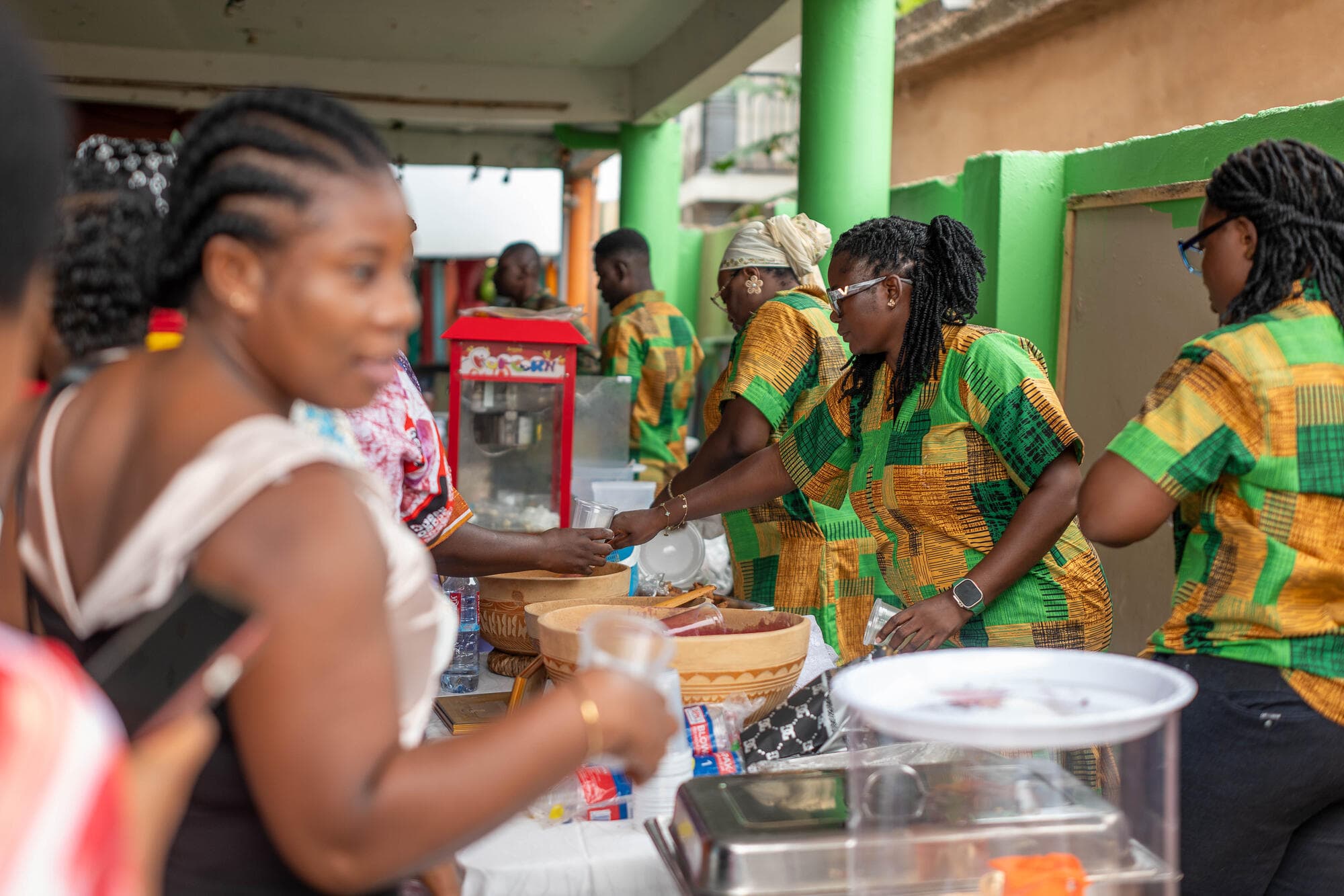 Staff in kente serving popcorn and drinks to families at the event
